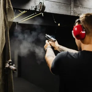 Man practicing handgun shooting at indoor range with ear protection